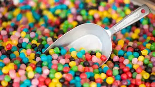Pelle métallique ramassant des bonbons et friandises sucrées colorées en vrac.