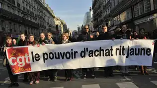 Manifestants brandissant une banderole de la CGT indiquant "le pouvoir d'achat rit jaune".